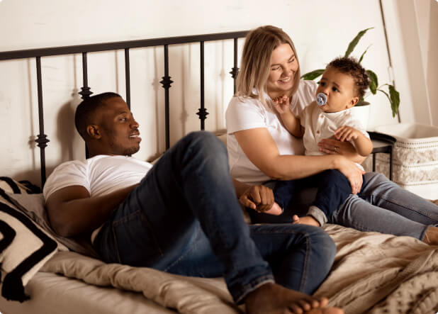 man, woman and child sitting on a bed